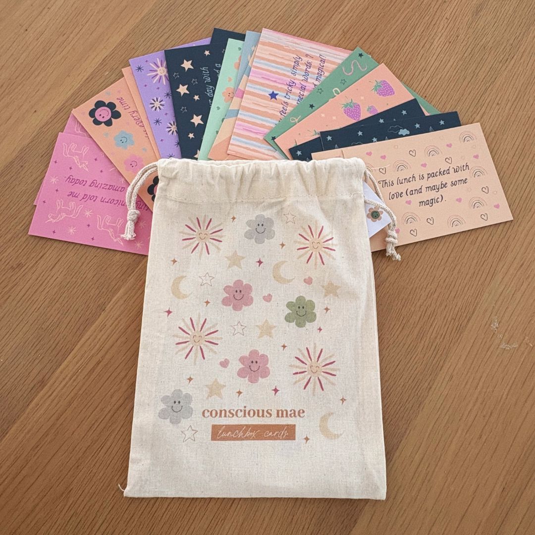 Set of colorful cards in a drawstring bag with 'conscious mae' branding on a wooden surface.