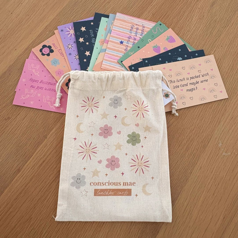 Set of colorful cards in a drawstring bag with 'conscious mae' branding on a wooden surface.