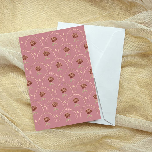Pink card with floral pattern and white envelope on a sheer fabric background