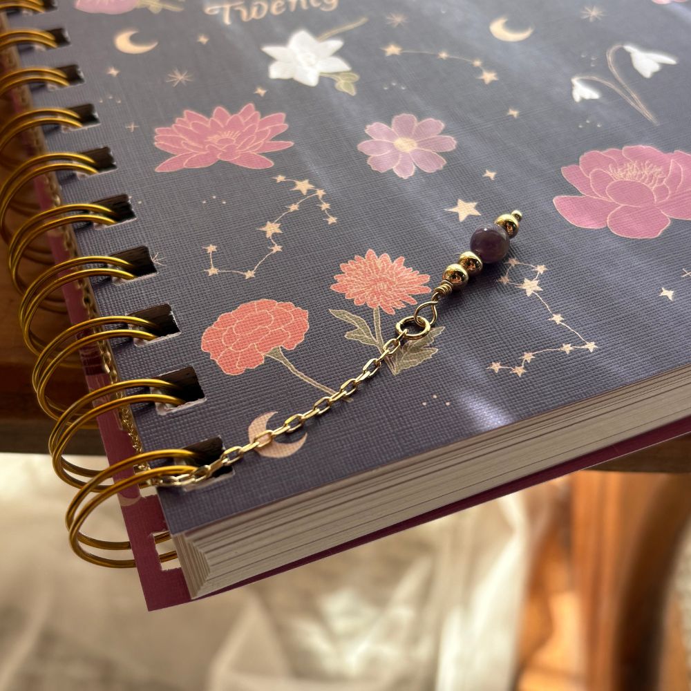 Notebook with floral design and a decorative keychain on a soft background