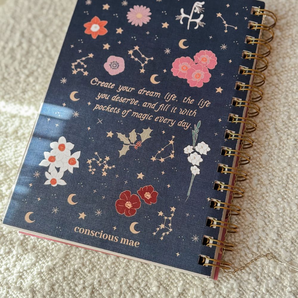 Notebook with decorative cover featuring flowers, stars, and text on a textured surface