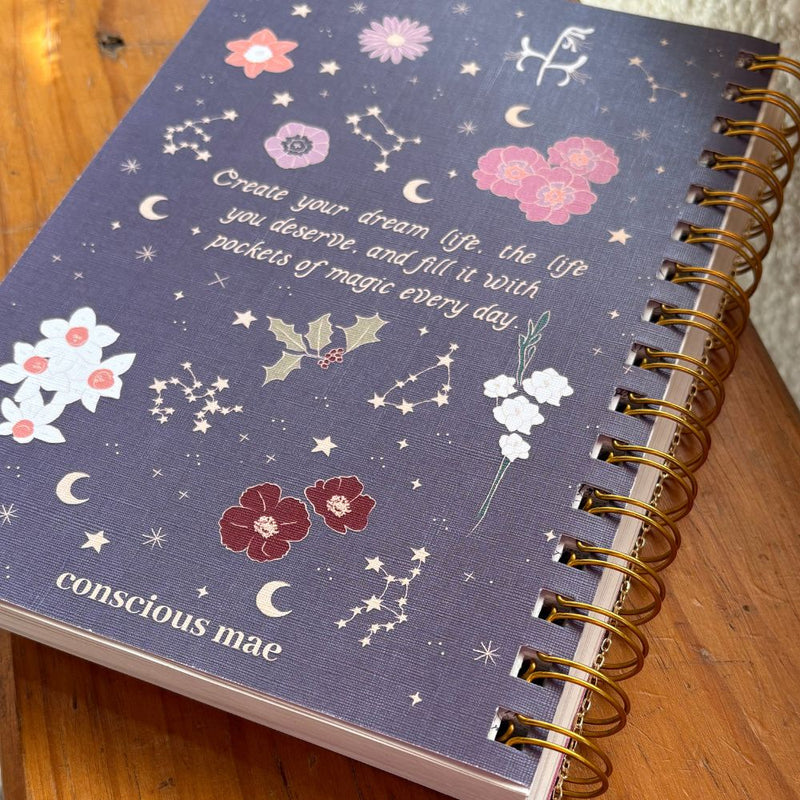 Purple 2026 diary with floral and celestial designs on a wooden surface