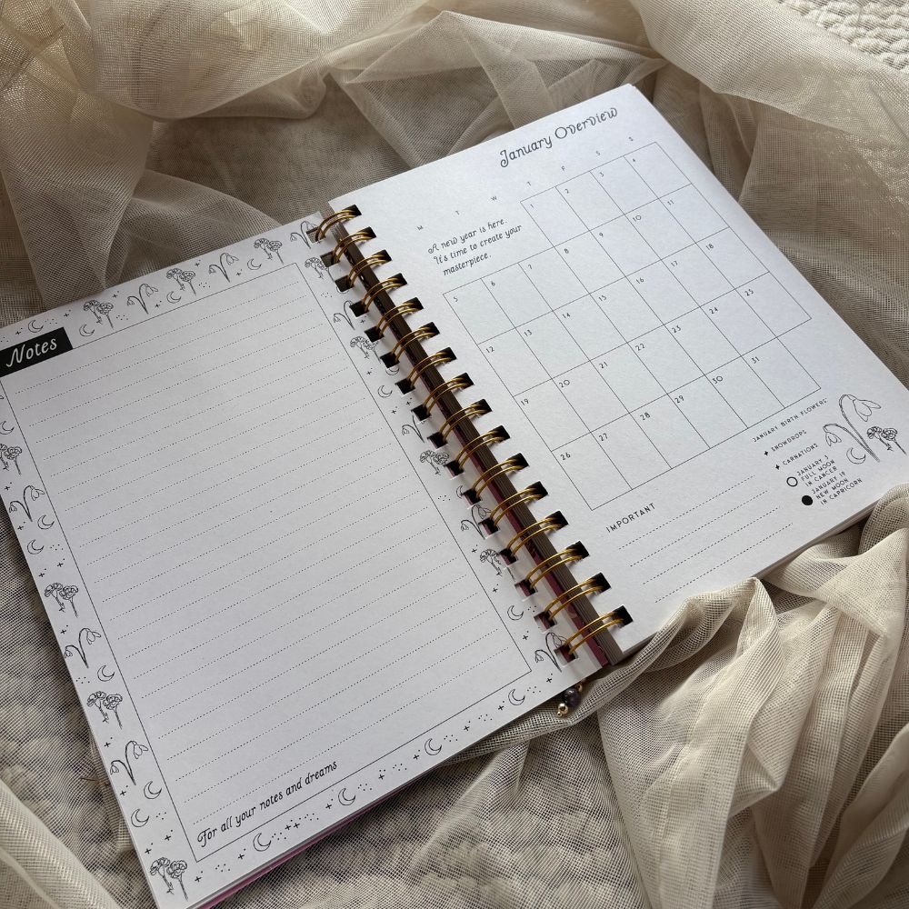 Open planner with monthly overview on a soft fabric background