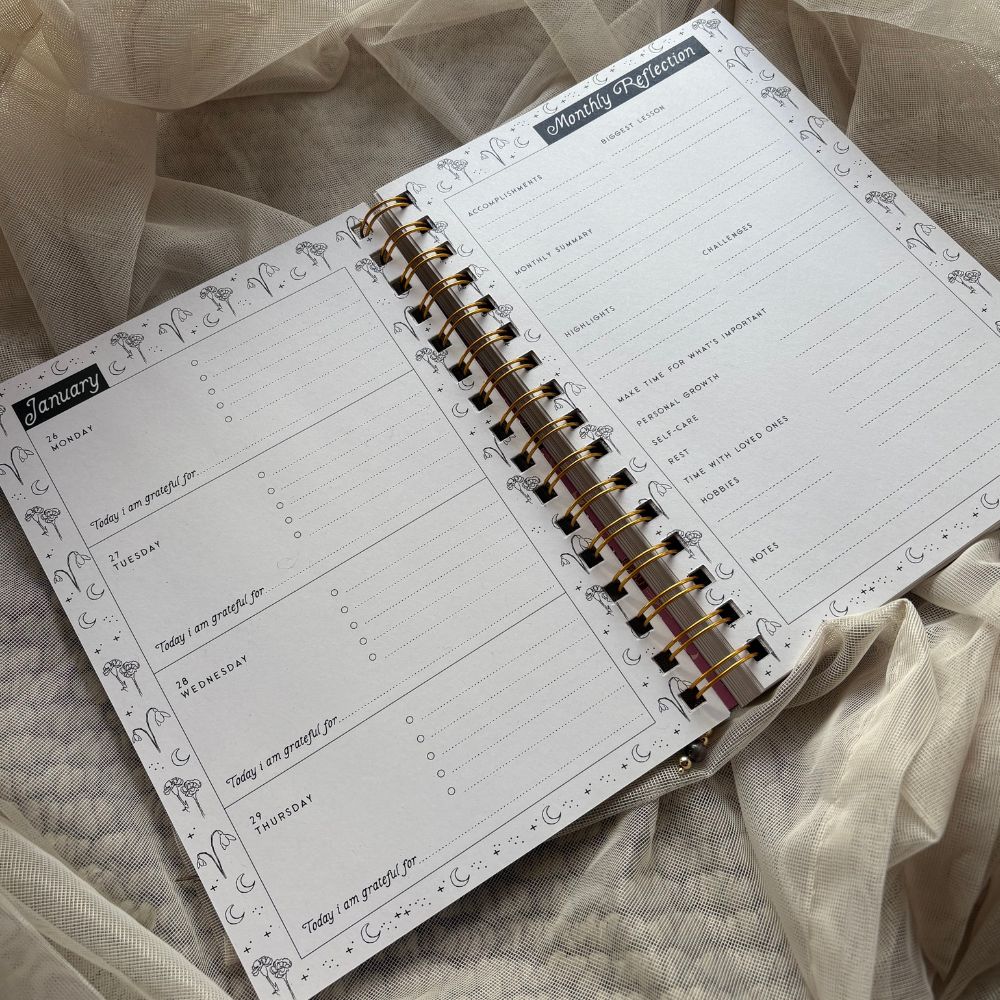 Open planner with monthly reflection page on a soft fabric background