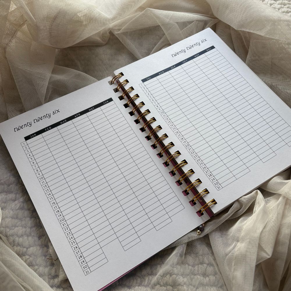 Open planner with grid year calendar layout on a soft fabric background