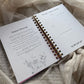 Open planner with spiral binding on a soft fabric background